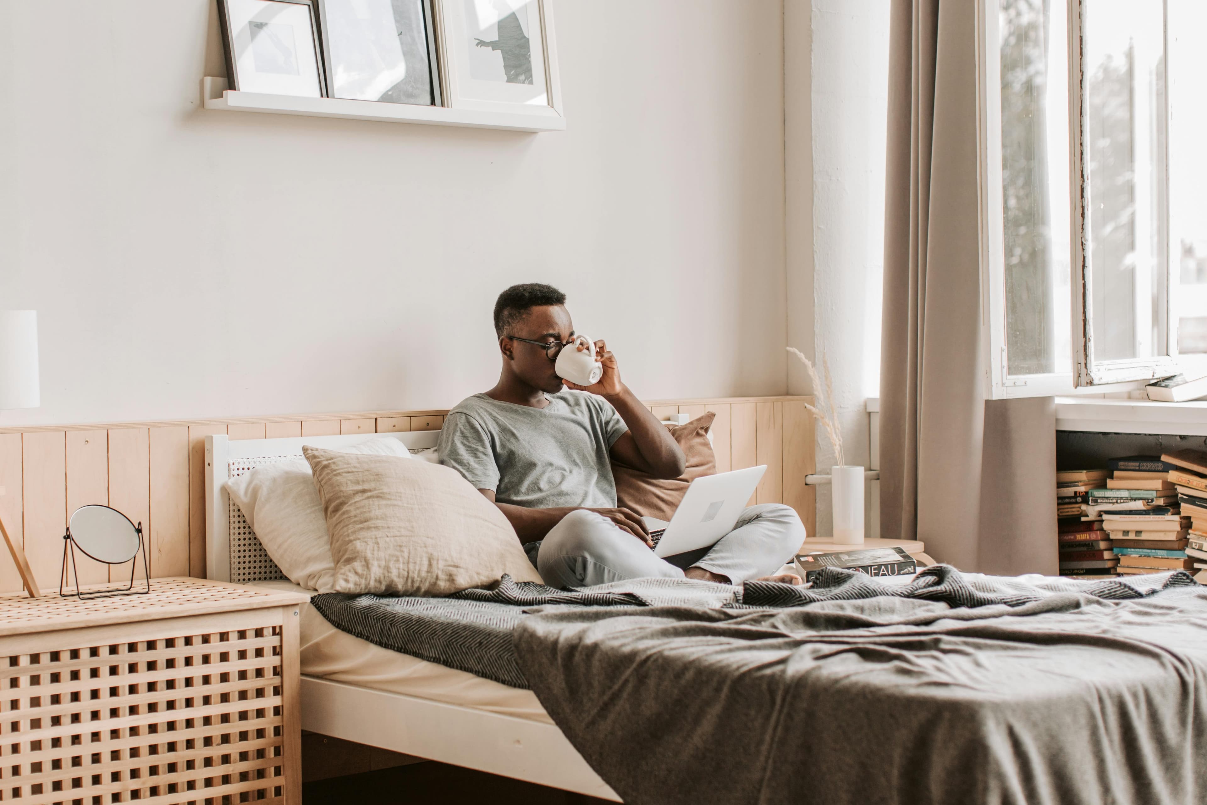 Man on bed with laptop and coffee